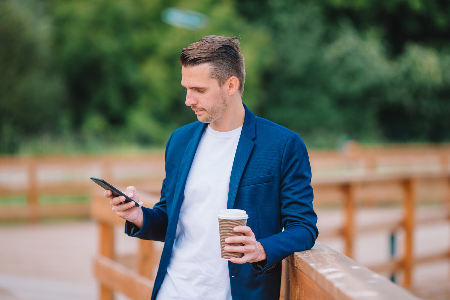 A man uses a smartphone and drinks coffee